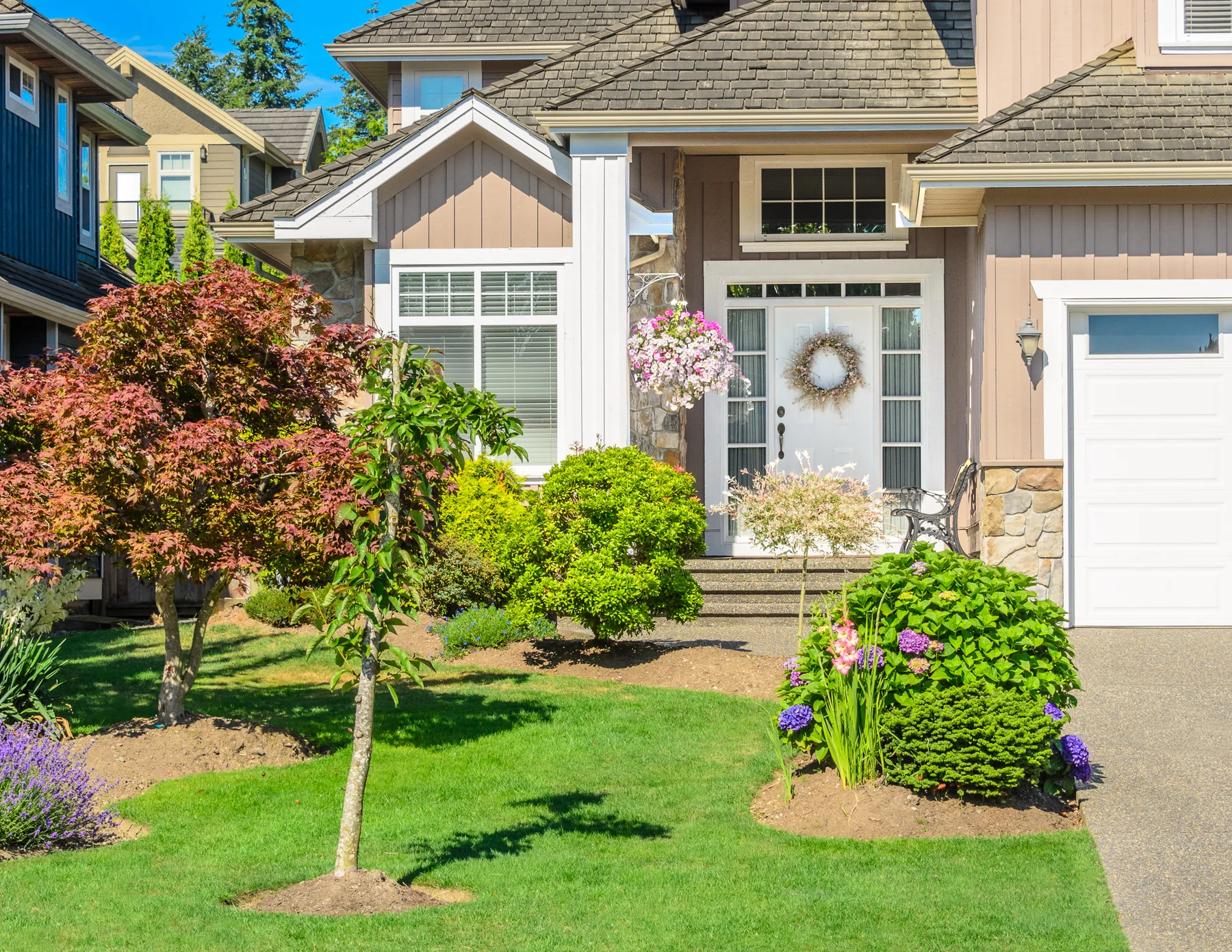 Residential landscape with spring shrubs, flowers, and a maintained lawn