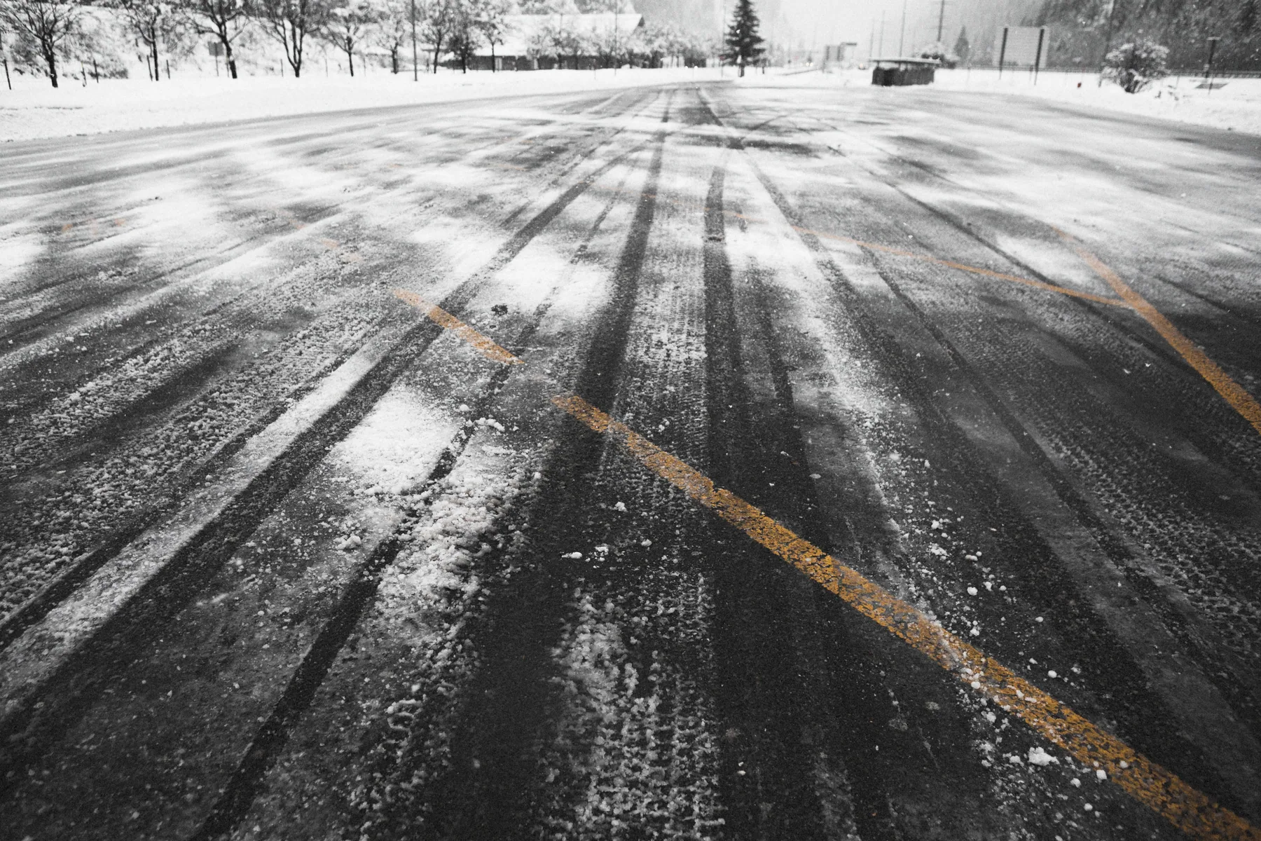 Snow-covered pavement with tire tracks after winter weather